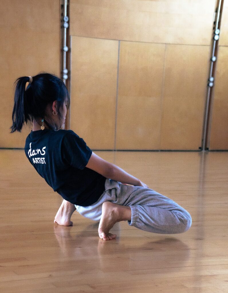 An image of a dancer in a crouch leaning backwards.