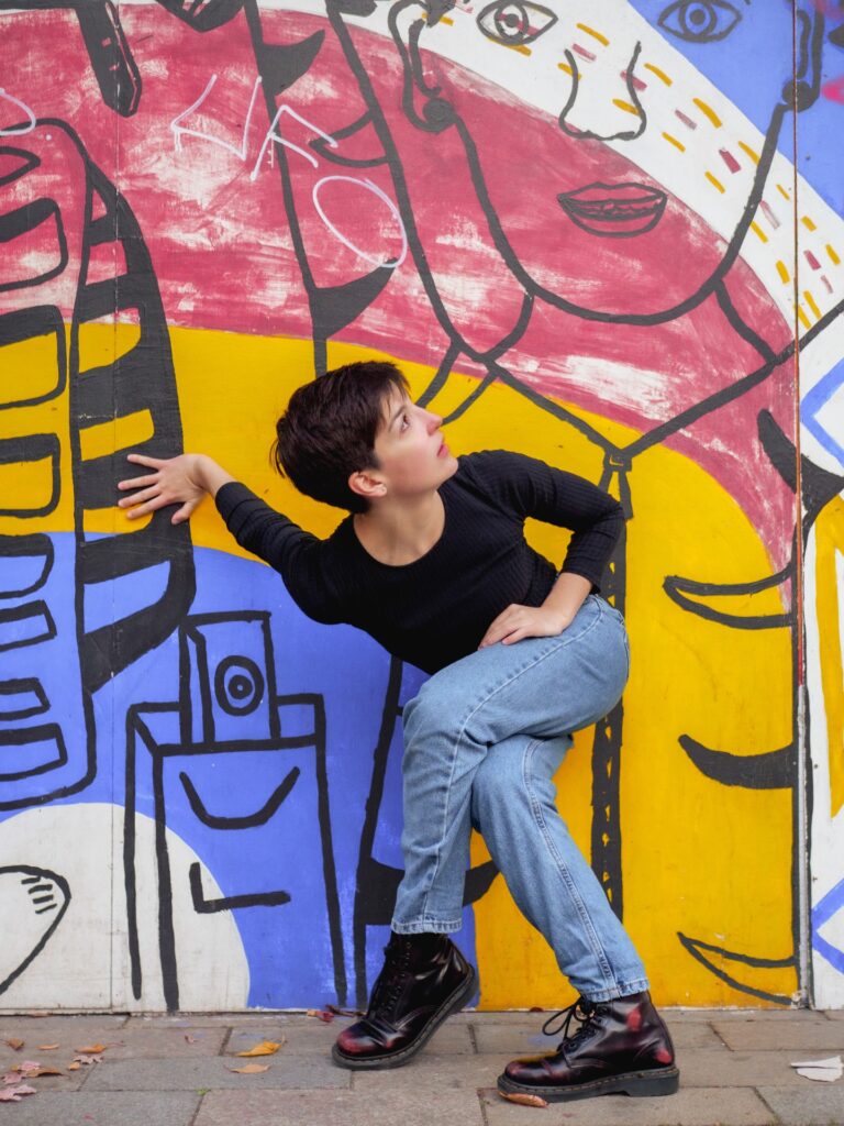 An image of a dancer in front of a colourful wall.